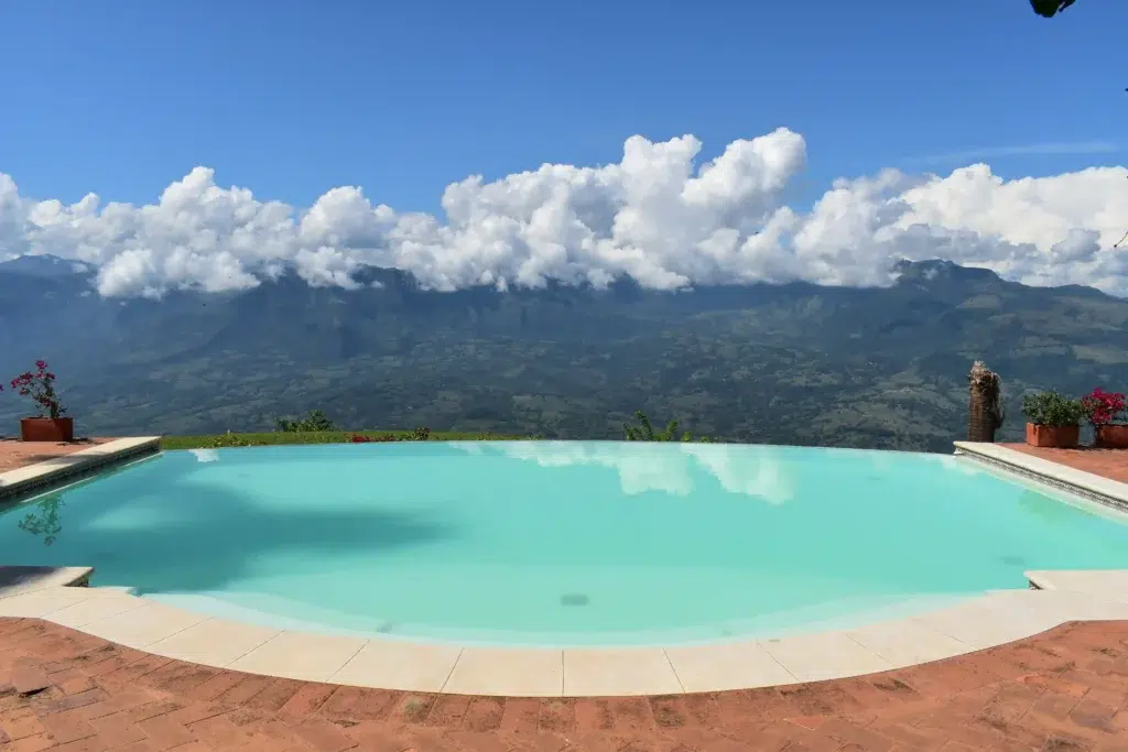 Piscina infinita con vista panorámica a las montañas y cielo azul en Antioquia. Diseño de piscinas de lujo por Piscinas Bluespace