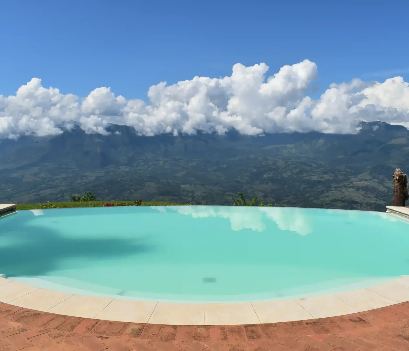 Piscina infinita con vista panorámica a las montañas y cielo azul en Antioquia. Diseño de piscinas de lujo por Piscinas Bluespace